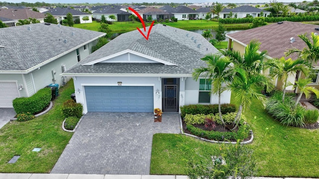 521 SE Plumeria Dr, Port Saint Lucie, FL 34984 - ranch-style home featuring a garage, a residential view, roof with shingles, decorative driveway, and stucco siding