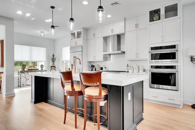 13496 Bernoulli Way, Palm Beach Gardens, FL 33418 - kitchen featuring wall chimney range hood, appliances with stainless steel finishes, light wood-style floors, light countertops, and recessed lighting