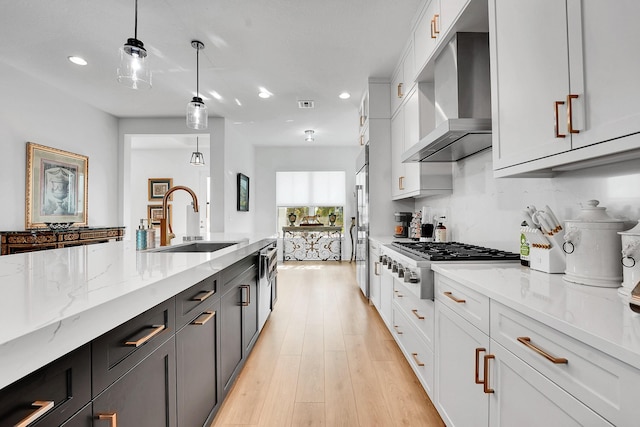 13496 Bernoulli Way, Palm Beach Gardens, FL 33418 - kitchen featuring wall chimney exhaust hood, stainless steel gas stovetop, white cabinets, recessed lighting, and light stone counters