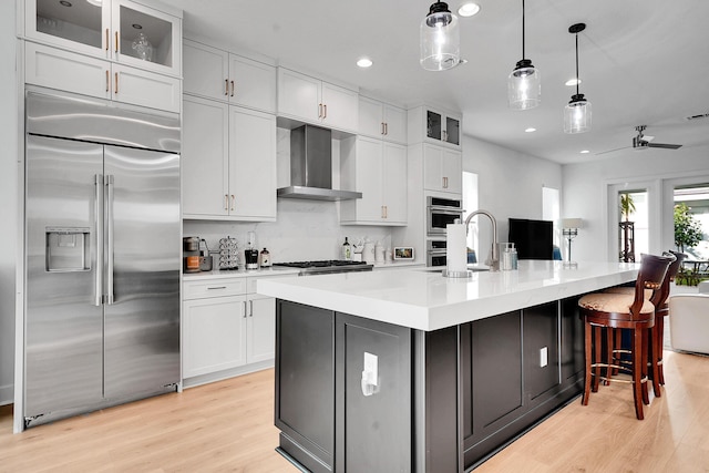 13496 Bernoulli Way, Palm Beach Gardens, FL 33418 - kitchen with stainless steel appliances, wall chimney exhaust hood, recessed lighting, light wood-style floors, and white cabinetry