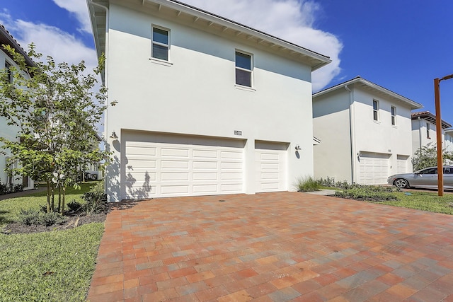 13496 Bernoulli Way, Palm Beach Gardens, FL 33418 - view of side of property featuring a garage, stucco siding, and decorative driveway