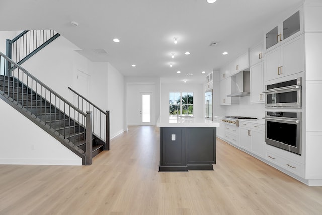 13496 Bernoulli Way, Palm Beach Gardens, FL 33418 - kitchen with wall chimney exhaust hood, light wood-style floors, stainless steel appliances, recessed lighting, and light countertops