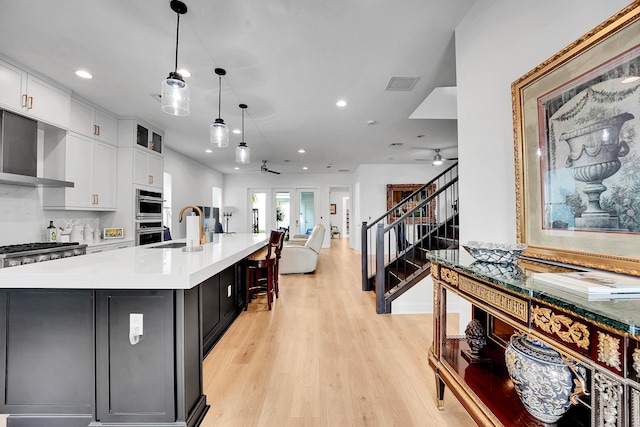 13496 Bernoulli Way, Palm Beach Gardens, FL 33418 - kitchen with a ceiling fan, wall chimney exhaust hood, recessed lighting, white cabinets, and light countertops