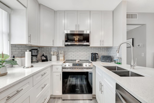 313 Saxony Unit G, Delray Beach, FL 33446 - kitchen featuring appliances with stainless steel finishes, light stone countertops, decorative backsplash, and white cabinetry