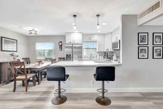 313 Saxony Unit G, Delray Beach, FL 33446 - kitchen with appliances with stainless steel finishes, a peninsula, a kitchen bar, and light wood-style flooring