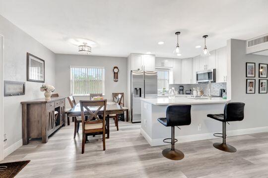 313 Saxony Unit G, Delray Beach, FL 33446 - kitchen featuring appliances with stainless steel finishes, light wood-style flooring, a peninsula, a kitchen breakfast bar, and recessed lighting
