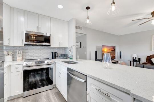 313 Saxony Unit G, Delray Beach, FL 33446 - kitchen with stainless steel appliances, light wood-style floors, tasteful backsplash, white cabinetry, and a peninsula