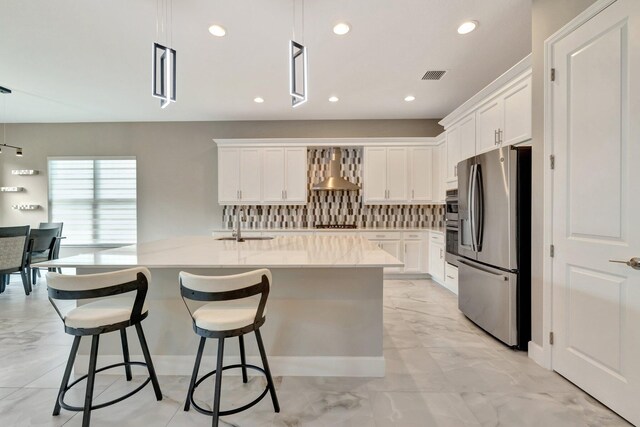 11535 SW Surf Springs Rd, Port Saint Lucie, FL 34987 - kitchen with appliances with stainless steel finishes, wall chimney exhaust hood, light marble finish flooring, white cabinets, and recessed lighting