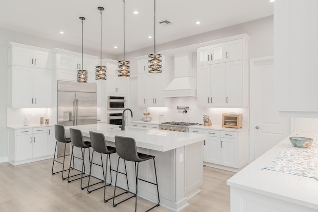 3153 SW Pond Apple St, Palm City, FL 34990 - kitchen featuring premium range hood, stainless steel appliances, a breakfast bar area, light wood-style floors, and recessed lighting