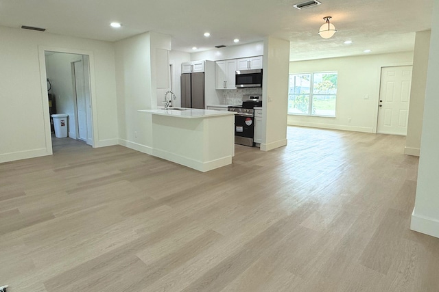 216 SE Fallon Dr, Port Saint Lucie, FL 34983 - kitchen with appliances with stainless steel finishes, open floor plan, light wood-style floors, recessed lighting, and white cabinets