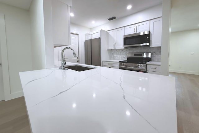 216 SE Fallon Dr, Port Saint Lucie, FL 34983 - kitchen with stainless steel appliances, light wood-style floors, backsplash, light stone countertops, and recessed lighting