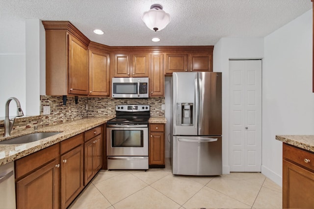 9850 Kamena Cir, Boynton Beach, FL 33436 - kitchen with appliances with stainless steel finishes, brown cabinets, decorative backsplash, a textured ceiling, and recessed lighting