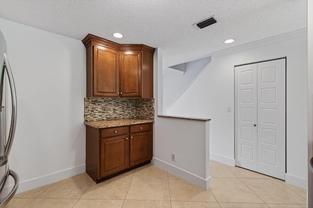 9850 Kamena Cir, Boynton Beach, FL 33436 - kitchen with tasteful backsplash, light stone counters, a textured ceiling, light tile patterned flooring, and freestanding refrigerator