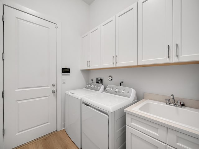 13058 Artisan Cir, Palm Beach Gardens, FL 33418 - laundry room featuring washer and dryer, cabinet space, and light wood-type flooring