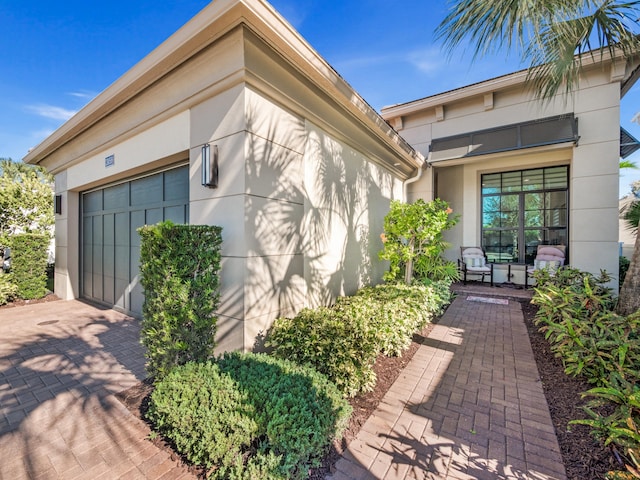 13058 Artisan Cir, Palm Beach Gardens, FL 33418 - doorway to property featuring stucco siding, decorative driveway, and an attached garage