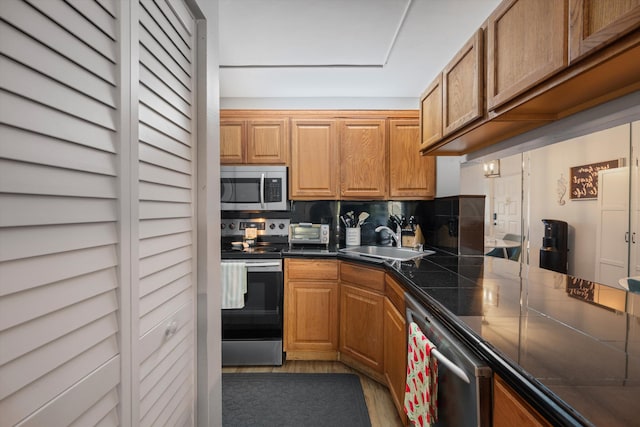 624 Sea Pine Way Unit A2, Greenacres, FL 33415 - kitchen featuring stainless steel appliances, dark countertops, backsplash, light wood-style flooring, and brown cabinetry