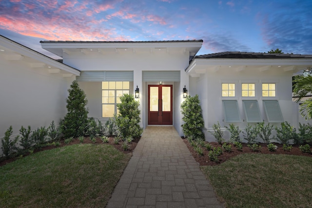 737 Nighthawk Way, North Palm Beach, FL 33408 - view of exterior entry featuring stucco siding, a lawn, and french doors