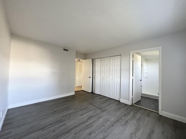 717 Gardens Dr Unit 106, Pompano Beach, FL 33069 - unfurnished bedroom featuring dark wood finished floors, a textured ceiling, and a closet