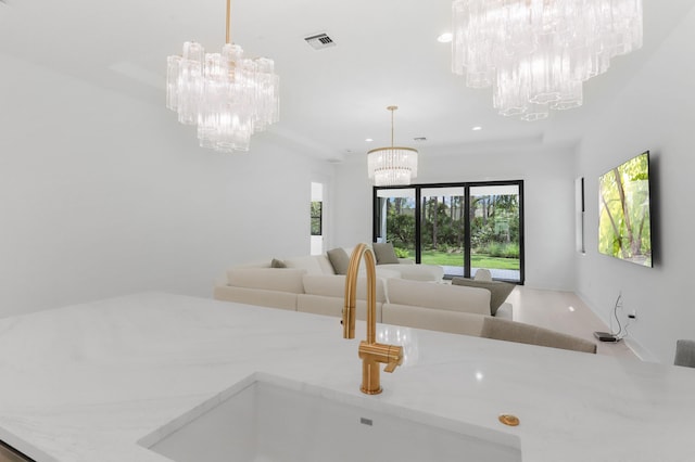 13214 Artisan Cir, Palm Beach Gardens, FL 33418 - kitchen with a chandelier, recessed lighting, open floor plan, pendant lighting, and light stone counters