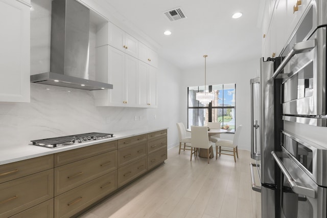 13214 Artisan Cir, Palm Beach Gardens, FL 33418 - kitchen with wall chimney exhaust hood, stainless steel gas cooktop, white cabinets, backsplash, and light countertops