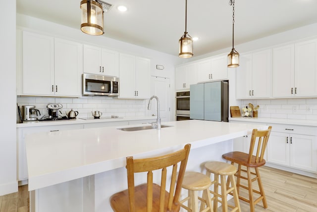 1416 Gopher Ter, Stuart, FL 34994 - kitchen with stainless steel microwave, a kitchen island with sink, tasteful backsplash, freestanding refrigerator, and a kitchen bar