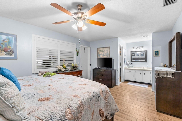 7376 W Oakridge Cir Unit C4320, Lake Worth, FL 33462 - bedroom featuring light wood-style flooring, ensuite bath, a textured ceiling, and a ceiling fan