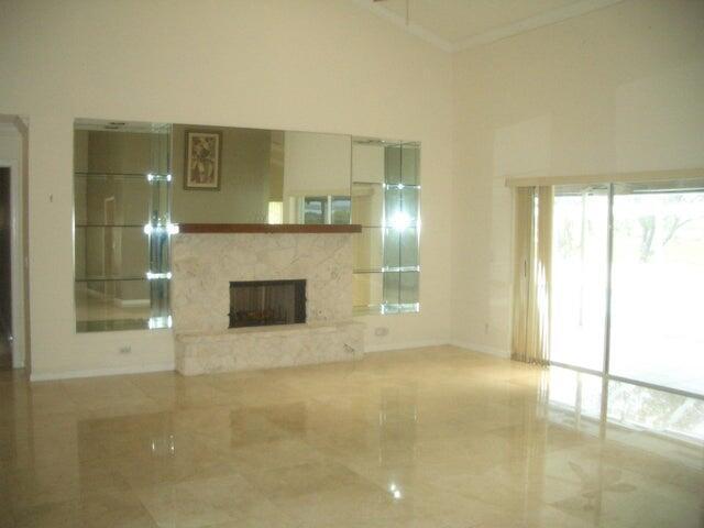 24 Dunbar Rd, Palm Beach Gardens, FL 33418 - unfurnished living room featuring a fireplace with raised hearth and ornamental molding