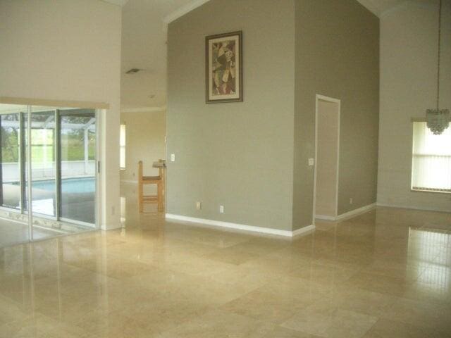 24 Dunbar Rd, Palm Beach Gardens, FL 33418 - tiled empty room with healthy amount of natural light and a towering ceiling