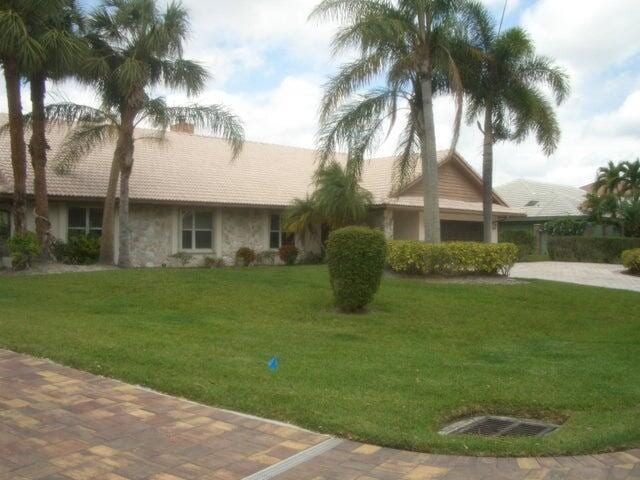 24 Dunbar Rd, Palm Beach Gardens, FL 33418 - ranch-style house with a front lawn, stone siding, and a chimney