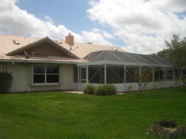 24 Dunbar Rd, Palm Beach Gardens, FL 33418 - rear view of property with a yard, a tile roof, a chimney, and stucco siding