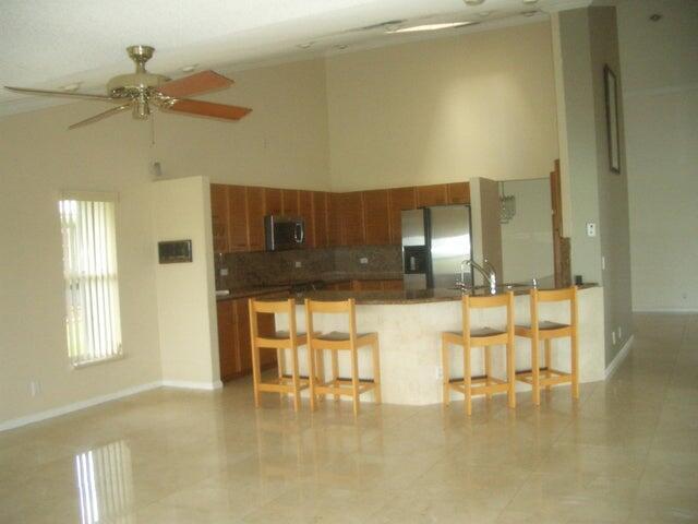 24 Dunbar Rd, Palm Beach Gardens, FL 33418 - kitchen featuring stainless steel appliances, brown cabinets, a breakfast bar area, and a high ceiling