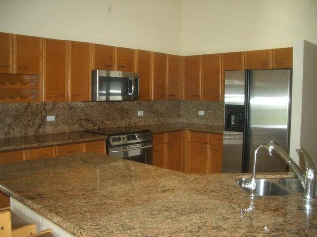 24 Dunbar Rd, Palm Beach Gardens, FL 33418 - kitchen featuring appliances with stainless steel finishes, tasteful backsplash, dark stone counters, and brown cabinets