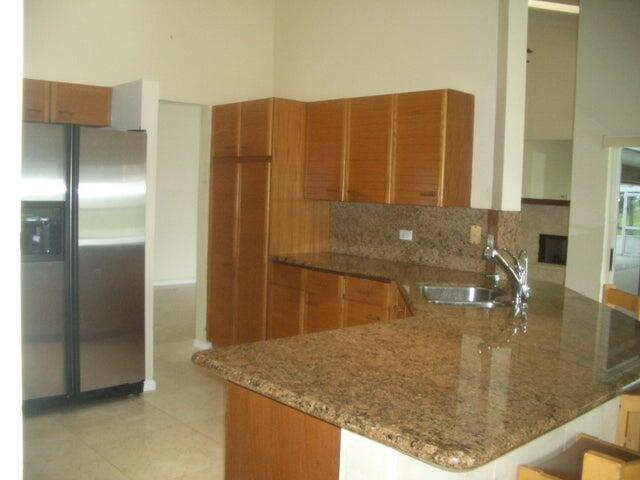 24 Dunbar Rd, Palm Beach Gardens, FL 33418 - kitchen with stainless steel refrigerator with ice dispenser, brown cabinets, stone countertops, and backsplash