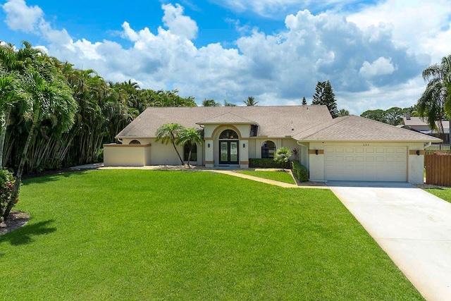 2282 NE Marlberry Ln, Jensen Beach, FL 34957 - view of front of property featuring french doors, stucco siding, an attached garage, and driveway