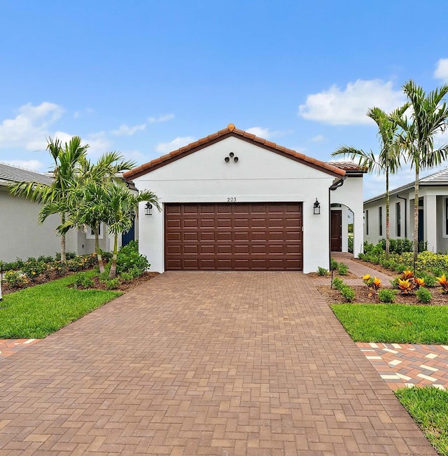 203 SE Via Sangro, Port Saint Lucie, FL 34952 - mediterranean / spanish-style home with stucco siding, a garage, decorative driveway, and a tile roof