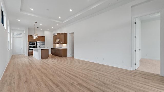 203 SE Via Sangro, Port Saint Lucie, FL 34952 - unfurnished living room with recessed lighting, light wood-type flooring, and a raised ceiling