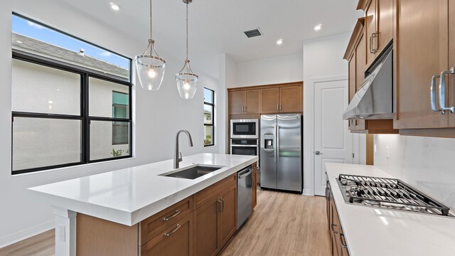 203 SE Via Sangro, Port Saint Lucie, FL 34952 - kitchen with appliances with stainless steel finishes, light wood-type flooring, light countertops, under cabinet range hood, and pendant lighting