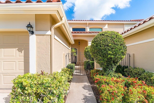 767 Windermere Way Unit 767, Palm Beach Gardens, FL 33418 - entrance to property featuring an attached garage, a tile roof, stucco siding, and a gate