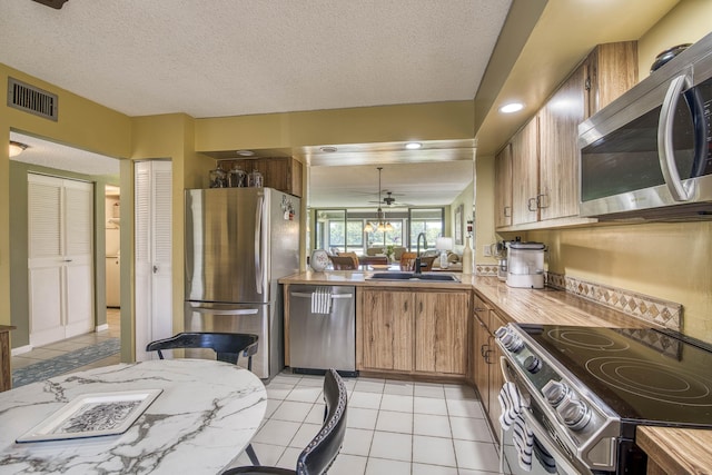 11186 Green Lake Dr Unit 202, Boynton Beach, FL 33437 - kitchen with stainless steel appliances, light countertops, brown cabinets, light tile patterned floors, and a textured ceiling