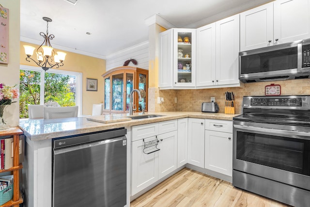 5404 E Pointe Villa Dr Unit 5406, Lighthouse Point, FL 33064 - kitchen featuring stainless steel appliances, a peninsula, a chandelier, crown molding, and backsplash