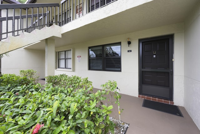 7626 Tahiti Ln Unit 104, Lake Worth, FL 33467 - view of exterior entry with stucco siding and a balcony