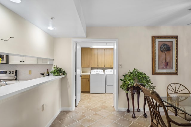 601 Seafarer Cir Unit 104, Jupiter, FL 33477 - kitchen with washing machine and dryer, stainless steel range, light tile patterned floors, light countertops, and decorative backsplash