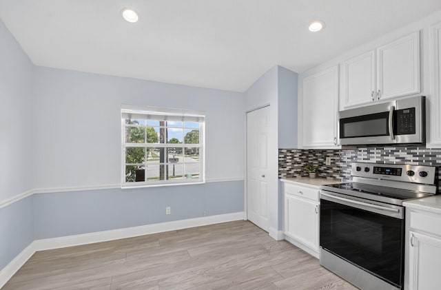 8182 Duomo Cir, Boynton Beach, FL 33472 - kitchen featuring appliances with stainless steel finishes, backsplash, light countertops, light wood-type flooring, and white cabinetry