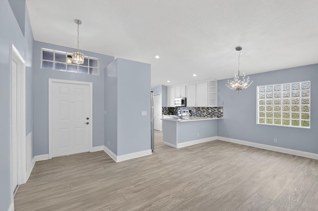 8182 Duomo Cir, Boynton Beach, FL 33472 - unfurnished living room featuring a chandelier, light wood-style flooring, and recessed lighting