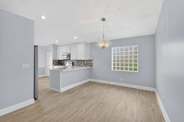 8182 Duomo Cir, Boynton Beach, FL 33472 - kitchen featuring appliances with stainless steel finishes, light countertops, a chandelier, white cabinetry, and tasteful backsplash