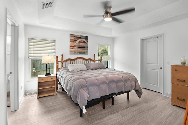 1037 SW Romaine Ln, Port Saint Lucie, FL 34953 - bedroom with a tray ceiling, light wood-type flooring, and a ceiling fan