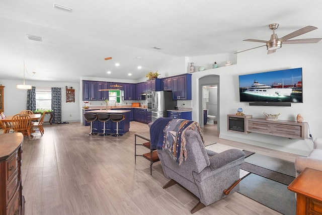 1037 SW Romaine Ln, Port Saint Lucie, FL 34953 - living area featuring vaulted ceiling, arched walkways, a ceiling fan, and light wood-style floors