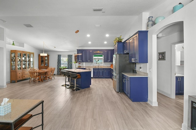 1037 SW Romaine Ln, Port Saint Lucie, FL 34953 - kitchen with blue cabinetry, light countertops, a kitchen breakfast bar, light wood-type flooring, and recessed lighting