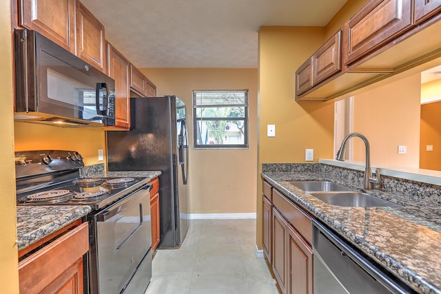 6545 SE Federal Hwy Unit 102, Stuart, FL 34997 - kitchen featuring black appliances, brown cabinetry, dark stone counters, and light tile patterned floors