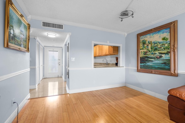 5961 NW 61st Ave Unit 203, Tamarac, FL 33319 - foyer featuring a textured ceiling, light wood-type flooring, and crown molding